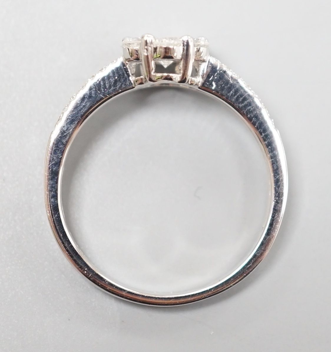 A modern 18k white metal and seven stone diamond cluster ring, with diamond chip set split shoulders, size M, gross weight 3 grams
